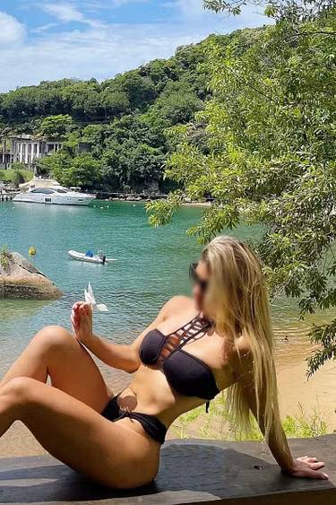 Blonde woman sitting in front of a beach